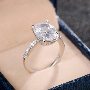 Close-up of silver ring with oval-cut zirconia and side pave stones in a blue box