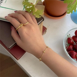 Detail of twisted gold ring and beaded bracelet worn together in a vintage setting