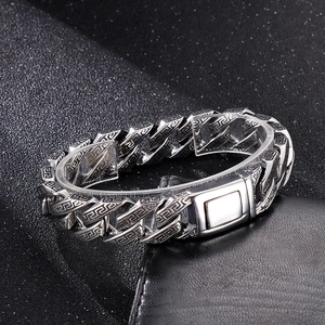 Close-up of vintage steel chain bracelet with Greek key pattern on black leather