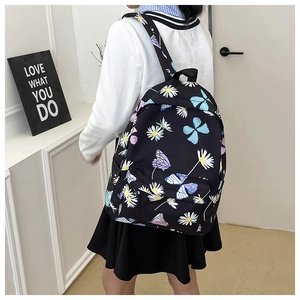 Side view of black backpack with butterfly and daisy prints featuring side mesh pocket