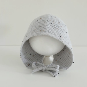 Détail du bonnet en maille grise mouchetée pour bébé avec texture douce et nœud à nouer