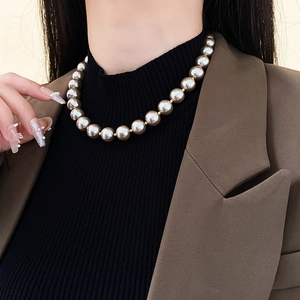 Detail of 12mm champagne baroque pearls on model with black turtleneck and blazer