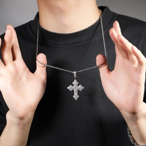 Gros plan d'un pendentif croix en argent serti de zircons avec une chaîne torsadée
