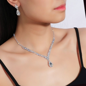 Elegant silver teardrop crystal necklace and earrings jewelry set worn by a female model