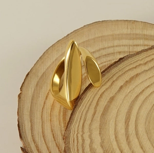 Macro view of a geometric 18k gold plated stainless steel ring on a rustic wood stand