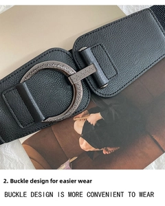 Close-up of vintage engraved silver buckle on a wide black elastic waist belt