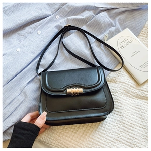 Détail d'un sac besace en cuir PU noir avec boucle dorée sur un tissu texturé