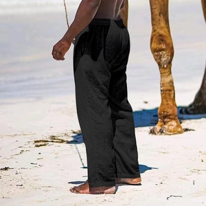 Detail of loose fit black cotton linen men trousers with elastic waist on beach backdrop