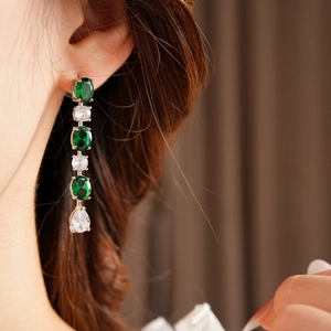 Gros plan de boucles d'oreilles pendantes avec pierres vertes et blanches sur un mannequin