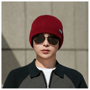 Close-up of red ribbed knit beanie with woven brand label and thick warm texture