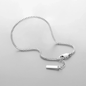 Close-up of silver stainless steel box chain bracelet with lobster clasp and tag