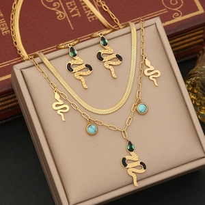 Double-layered gold snake pendant necklace and earring set with green crystals in box