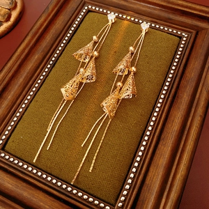 Détail de boucles d'oreilles pompons dorées avec cœurs en cristal sur velours