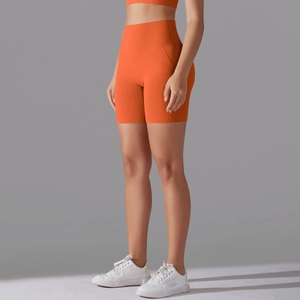 Detail showing high-waist orange yoga shorts with seamless design and compression fit