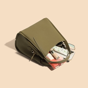 Olive green leather bucket bag with daily items inside shown from a top-down view