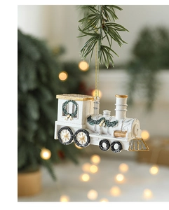 Detailed view of white and gold resin train ornament hanging on a green pine branch