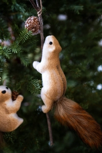 Lifelike squirrel ornament with fluffy tail climbing on a Christmas tree branch