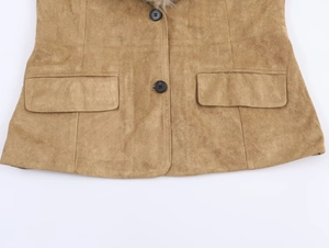Detail of tan suede jacket featuring black buttons and symmetrical flap pockets