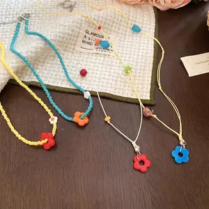 Colorful beaded necklaces with flower pendants in vibrant dopamine style on wooden surface