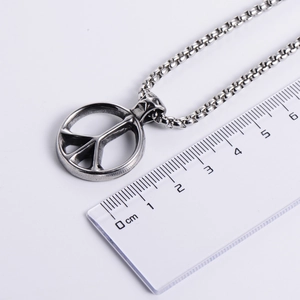 Classic silver stainless steel peace sign pendant necklace with a pearl chain on a ruler