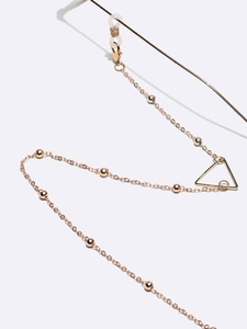 Detail of rose gold glasses chain with metal beads and a geometric triangle pendant