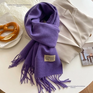 Close-up of soft purple cashmere-like scarf with fringe details and woven brand label