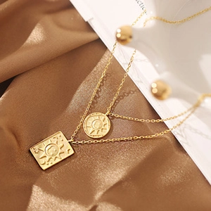 Detail view of double-layered gold necklace with sun and moon pendants on satin fabric