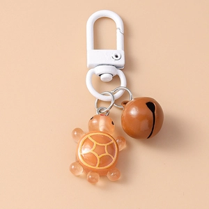 Detail of cute resin turtle keychain with brown metal bell and secure metal clasp