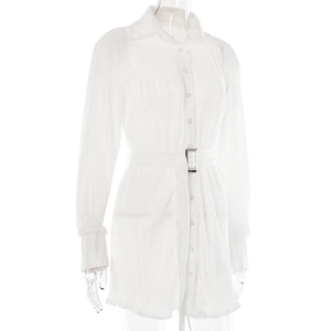 Close-up of white pleated shirt dress featuring long sleeves and silver square buckle belt