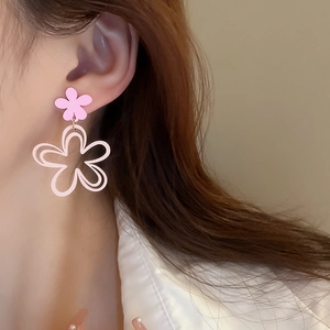 Close-up of pink cutout flower earrings worn by a model in a minimalist style
