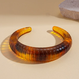 Macro detail of amber resin bangle showing unique horizontal texture and rich brown tones