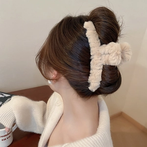 Fuzzy cream faux fur hair claw clip styled on woman's hair in cozy indoor setting