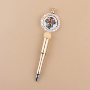 Detail of gold beaded pen with pearl ring and 'He lives' religious cross print