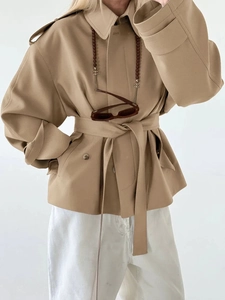 Detail view of khaki short trench coat featuring classic shoulder tabs and a waist belt