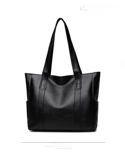 Detail of black pebbled leather tote bag showing side pocket and durable shoulder straps