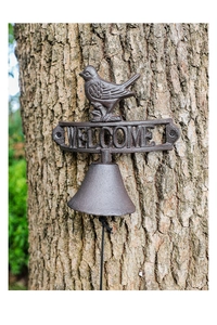 Macro detail of rustic cast iron welcome bell with bird statue on a wooden trunk