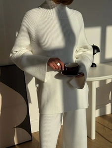 Detailed texture of white ribbed knit fabric on turtleneck sweater and wide-leg trousers
