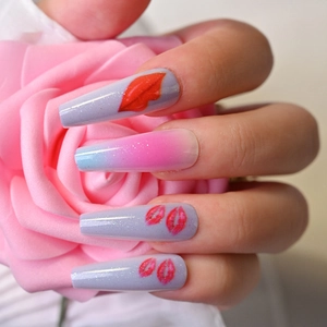 Detail of long coffin press-on nails with blue-pink gradient and red lip glitter pattern