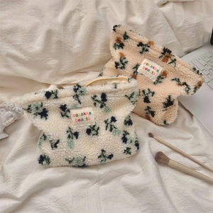 Close-up of floral plush makeup bags in white and tan colors with textured lamb wool
