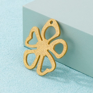 Frosted gold stainless steel hollow flower pendant displayed on a light blue block