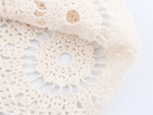 Gros plan sur un tricot au crochet blanc cassé avec motifs floraux ajourés complexes