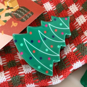 Detail of green Christmas tree hair claw clip with colorful dots on a festive knit background