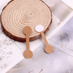 Brown kraft paper ring price tags and jewelry labels displayed on a circular wood base