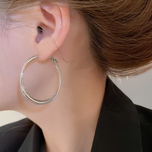 Close-up of large double-layer silver hoop earrings worn by a model in profile view