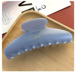 Detail of elegant ink blue acetate hair claw with Barrette La France text on wood tray