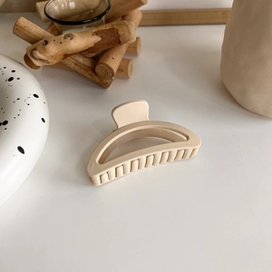 Close-up of matte cream beige hair claw clip with elegant minimalist arch design