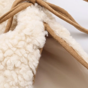 Detail of warm off-white lamb wool vest featuring brown drawstring and soft texture