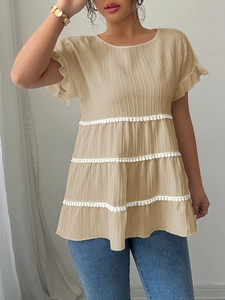 Close-up of beige textured blouse featuring tiered layers and white pom-pom lace trim detail