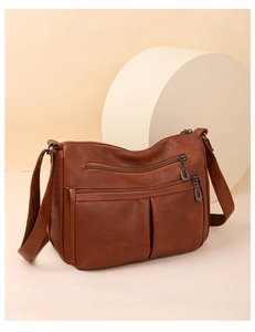 Detail view of multi-pocket dark brown crossbody bag with adjustable strap and zippers