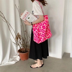 Detail of large pink leopard print canvas tote bag shown worn on shoulder in lifestyle setting